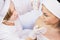 Top view photo of a woman client undergoes medical examination of the face by a cosmetician in gloves in beauty clinic.