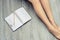 Top view photo of woman`s legs on wooden floor with opened diary