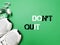Top view phrase DO NOT QUIT on green background with sport shoes, water bottle and earbuds.
