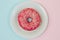 Top view picture of tasty sweet pink doughnut on white plate in