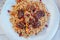 Top view of pilaf or plov with meat on a white plate.