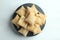 Top view of a pile of square puff biscuits on a black pastry stand