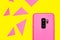 Top view of a pink smartphone on a yellow surface with colorful triangles on it