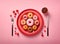 Top view on pink table served with red plate with different verity of donuts