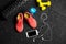 A top view of pink trainers, bottle for water, phone and small dumbells on a black background. Sports accessories.