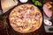 Top view on pizza with ham, onion and parmesan and white sauce with ingridients on brown wooden table. Picture for recipe or menu