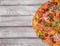 Top view of a pizza. Pizza with meat, cheese and vegetables on a wooden background. Italian cuisine concept. Copy space.