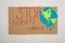 Top view of placard with painted globe and stop climate change lettering on grey background, global warming concept