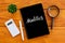 Top view of plant,calculator,pen,magnifying glass, and notebook written with Analytics on wooden background.