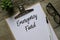 Top view of plant,glasses,pen and clipboard with white paper written with Emergency Fund on wooden background