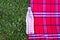 Top view of a plastic bottle with clean water lies on a red plaid against a background of green grass