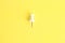 Top view of a plastic thumbtack on a yellow background