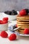 Top view of plate with pancakes with blackberries, raspberries and spoon, on white wooden table, bowls with raspberries and blackb