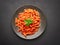 Top view plate of Penne all`Arrabbiata pasta on dark background