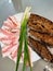 Top view of a plate with slices of bread, pork lard and onion feathers