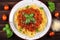 Top view of a plate of steaming Spaghetti Bolognese garnished with fresh basil leaves and grated Parmesan cheese