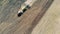 Top view of a plough sowing a massive field and raising dust