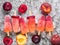 Top view of plum and peach popsicle on gray metal background