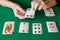 Top view of poker cards on green mat with woman`s hands playing solitaire