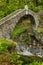 Top view on the Ponte Romano Intragna Bridge hiding in the valley with beautiful river covered with trees, close to