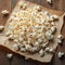 Top view of popcorn on paper, wooden background, copy space