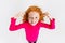 Top view portrait of little cute redheaded girl in pink sweater posing isolated over white studio background.