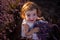 Top view portrait of little girl sitting in field among rows, collecting bouquet of purple lavender