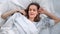 Top view portrait of young awakening woman stretching on bed. Medium close up shot on 4k RED camera