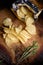 Top view on potato chips with fresh rosemary on wooden board. Open bag of salty snack.