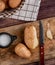 top view of potatoes with shell knife and salt on cutting board with other ones in basket on cloth on wooden background