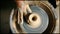 Top view of potter hands working on pottery wheel and making a pot