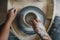 Top view of potter woman hands works at pottery wheel, potter makes new ceramic production