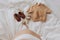 Top view of pregnant woman belly bump and stylish brown boho shoes, clothes and wooden toys for baby on white bed at home. Stylish