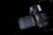 Top view professional digital camera with a zoom lens and a leather strap on a black background with copy space. View