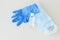 Top view of protective stuff, blue medical mask and glove, white bottle of sanitizer on light background.