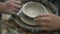 Top view of pupil making a ceramic bowl with help of teacher on pottery wheel in a workshop.