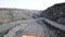 Top view of quarry dump truck. Dump truck traveling on dusty roads of open pit extraction of minerals. Heavy transport