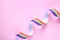 Top view of rainbow ribbon on pink background, space for text.