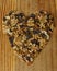 Top view of raisins with different dried fruits forming a heart on a woody background