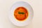 Top view of Ravioli Soup with basil in white bowl on white tablecloth