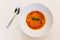 Top view of Ravioli Soup with basil in white bowl on white tablecloth with silver spoon