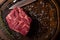 Top view of raw Chuck Eye beef steak seasoned with coarse salt and rosemary, on a dark wooden textured surface, with space for