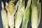 Top view of raw ears of maize on the black rural surface