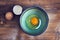 Top view of raw egg in bowl, eggshell on wooden table. Concepts of preparing for breakfast, cooking at home