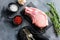 Top view raw pork chop steak and salt, pepper on black slate stone over grey textured backgroud