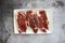 Top view of raw steak pieces in a plate on a gray surface under the lights