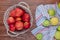 top view of red apples in basket with green ones on plaid cloth on wooden background