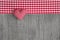 Top view of red checkered heart shape on a wooden grey shabby b