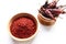 Top view of Red chilli pepper seedless flakes in wooden bowl on white background.