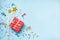 Top view of a red dotted gift box, golden magic wands, colorful confetti and ribbons over blue background. Celebration concept. Co